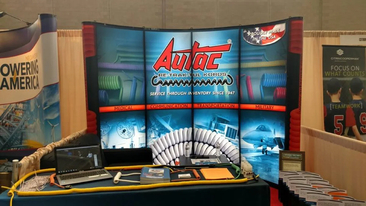 Autac USA trade show booth showing retractile cords for medical, communication, transportation, and military industries
