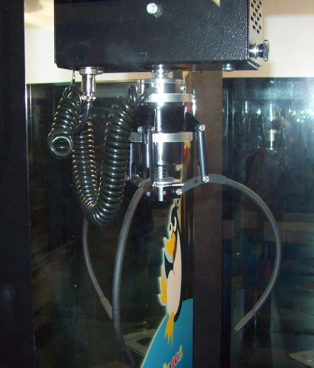 Black curly cords feeding the claw mechanism of an arcade crane game
