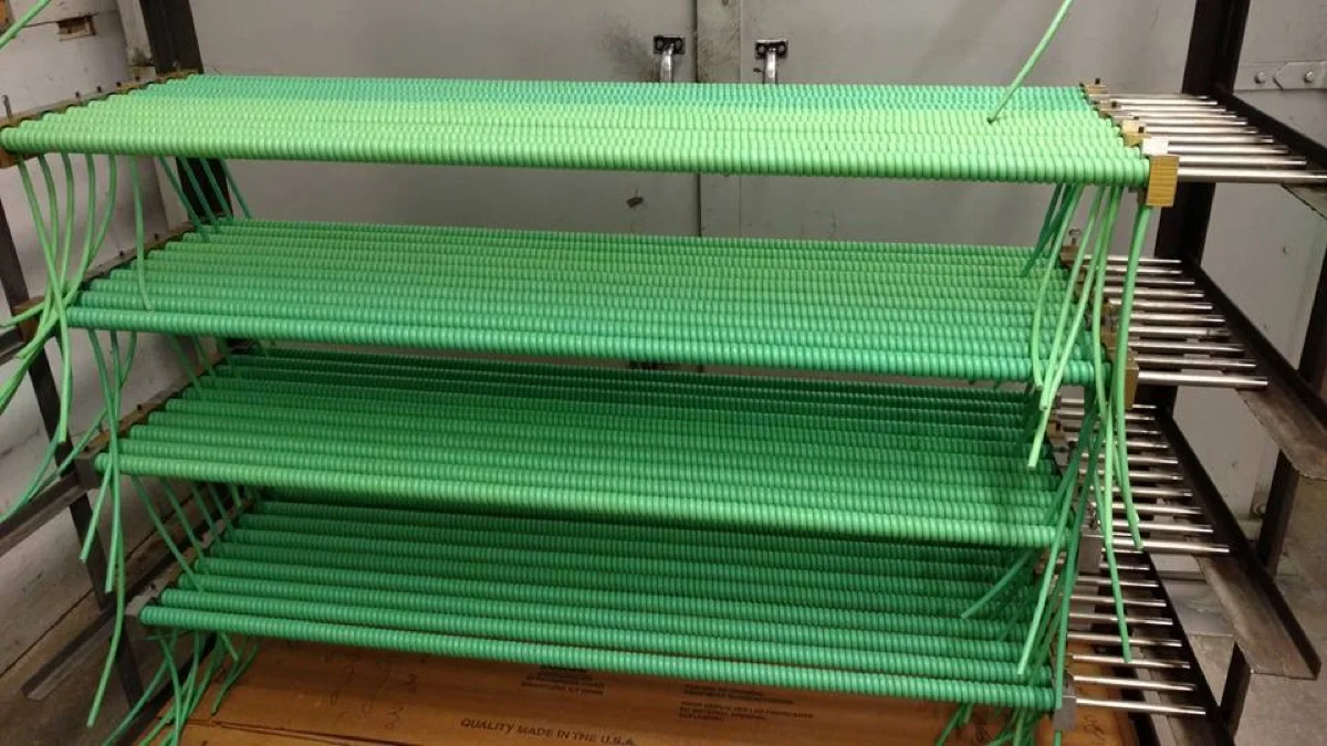 Rack of custom green coiled cables wound on mandrels