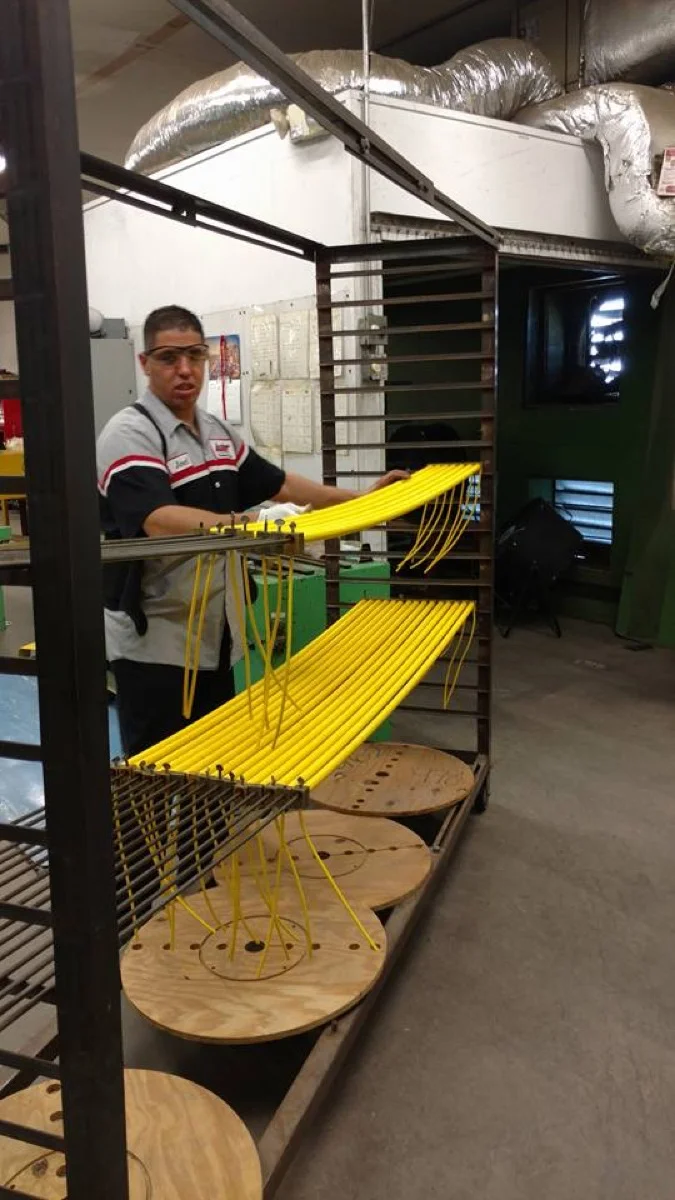 Autac technician racking yellow coiled cords on mandrels for heat setting